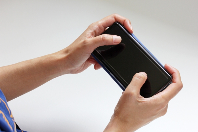 スマートフォンを横向きで持つ男性